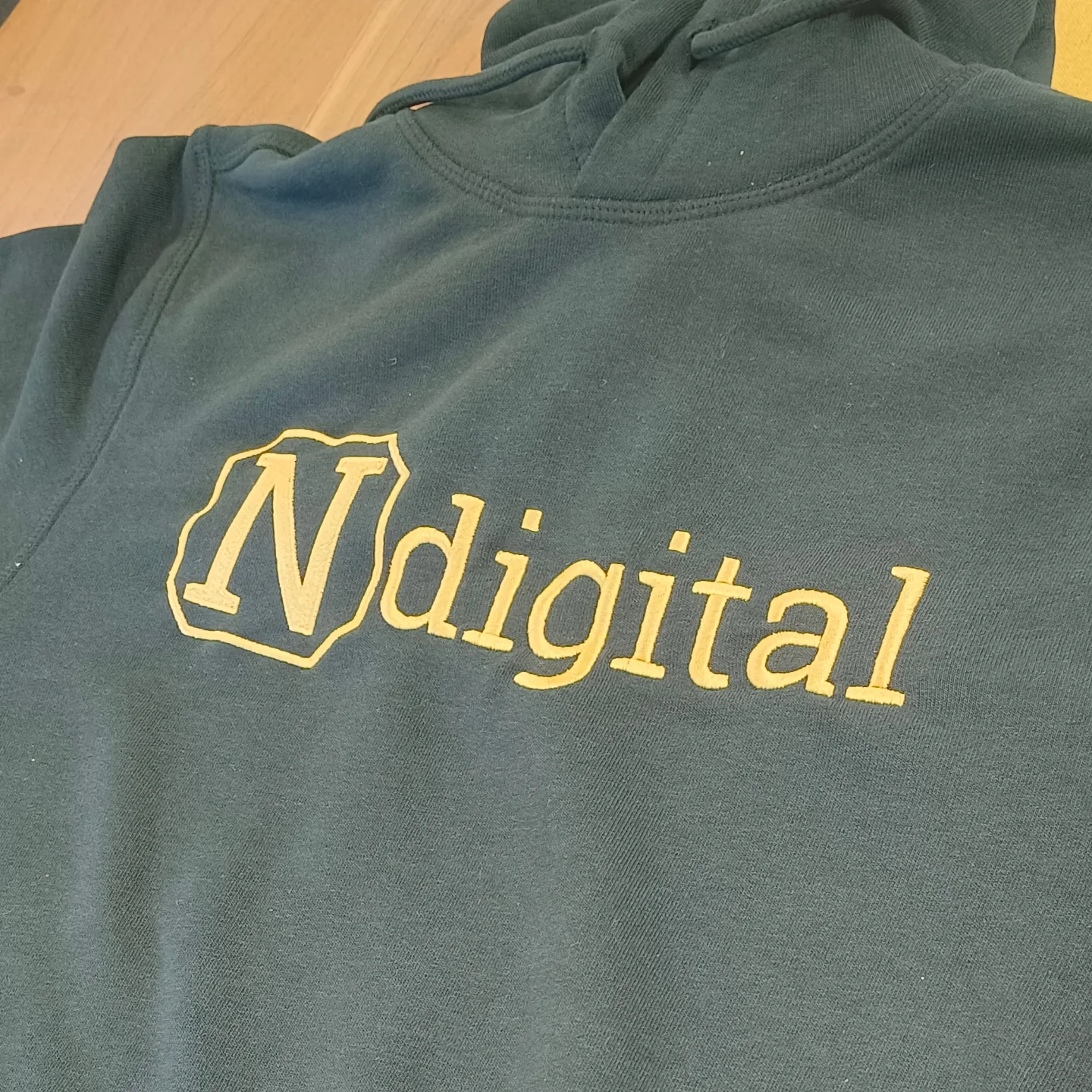 Dunkelgrüner Hoodie mit goldenem Logostick für N digital